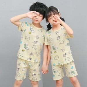 Zweiteiliger weißer Pyjama mit Cartoon-Muster für Kinder mit zwei Kindern, die den Pyjama tragen, und einem grauen Hintergrund