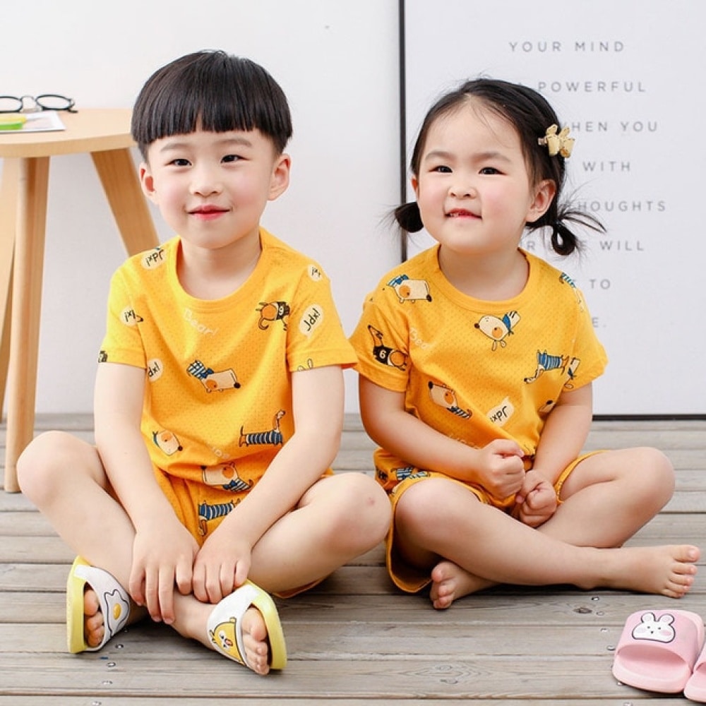 Gelber zweiteiliger Pyjama mit Cartoonmuster für Kinder mit zwei kleinen Kindern, die den Pyjama tragen