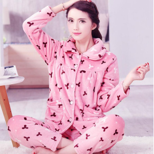 Warmer, dickerer Fleece-Pyjama für Frauen in Rosa, der von einer Frau getragen wird, die auf einem Teppich in einem Haus sitzt