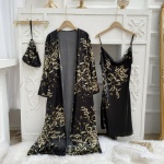 Sexy schwarzer Pyjama mit Blumenmuster, der an Kleiderbügeln vor einer weißen Wand mit Zierleisten und auf einer weißen Pelzdecke hängt
