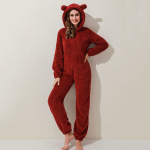 Rote Fleece-Pyjama-Kombination, die von einer Frau vor einer beigefarbenen Wand getragen wird