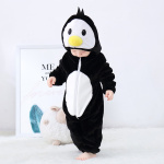 Baby im schwarzen Pyjamaanzug in Form eines Pinguins, der auf seine Füße schaut