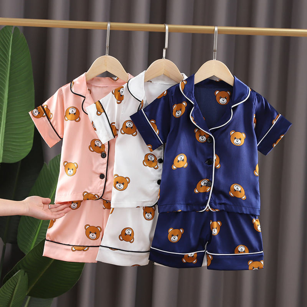 Drei Kinderpyjamas auf Kleiderbügeln mit Bärenmotiven in rosa, weiß und blau